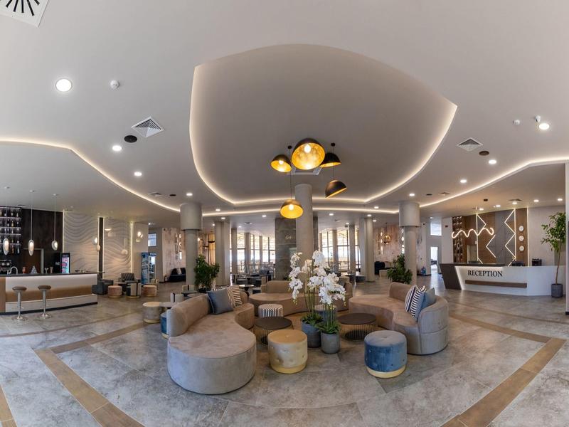 Ruime hotellobby met moderne zitgedeeltes en stijlvolle verlichting.