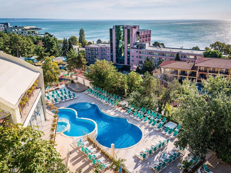 Groot buitenzwembad van een hotel met ligstoelen en uitzicht op zee.