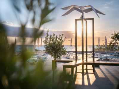 Moderní socha na terase s výhledem na přístav za západu slunce.