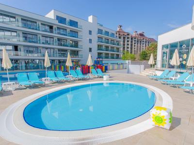 Piscine ronde extérieure avec transats et parasols à côté d'un bâtiment d'hôtel.