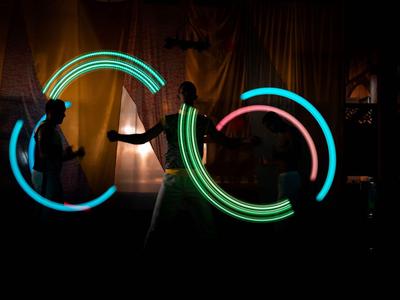 Personnes avec des cerceaux LED lumineux dans une pièce sombre lors d'un spectacle de lumière.