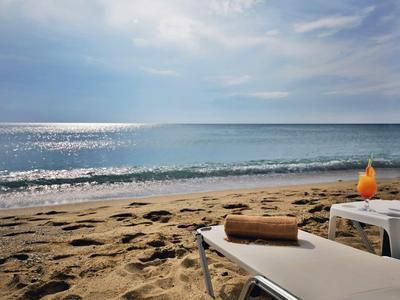 Strand met ligstoel, handdoek en drankje bij rustige zee onder bewolkte lucht