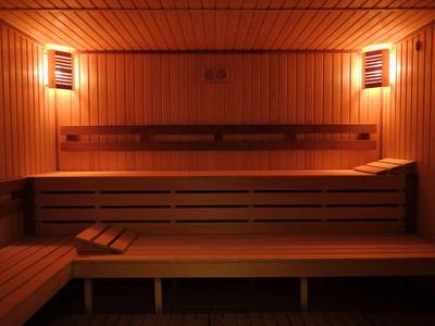Interieur van een houten sauna met banken en gedimde verlichting aan de muren.