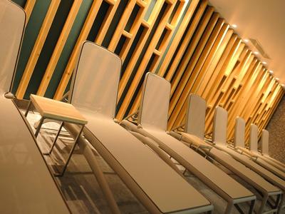 Vijf ligstoelen met kussens voor een muur met decoratieve houten latten in warm licht