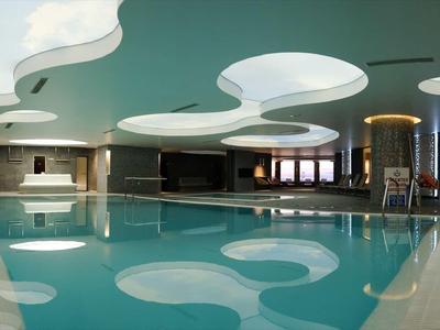Een modern binnenzwembad met gebogen witte plafondaccenten en grote ramen.