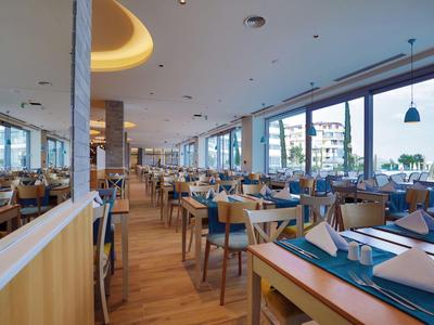 Grande salle à manger moderne avec mobilier en bois et vue sur la ville à travers de grandes fenêtres.