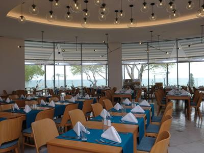 Restaurant moderne et lumineux avec de grandes fenêtres et des tables bleues.