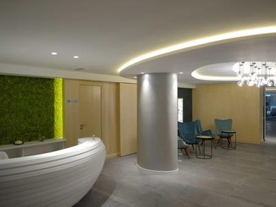 Moderne hotel lobby met ronde receptiebalie, groene wandaccent en zithoek.