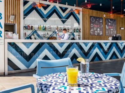 Stůl na terase s nápoji před moderním barem s modro-bílým cikcak vzorem.