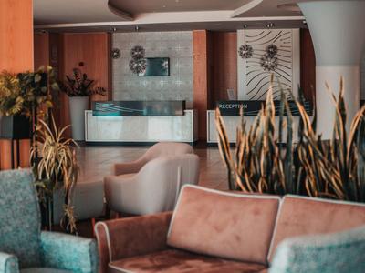 Moderní hotelová hala s posezením a rostlinami v popředí.