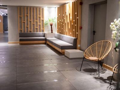 Světlá hotelová hala s moderním posezením a dřevěnými stěnovými panely.