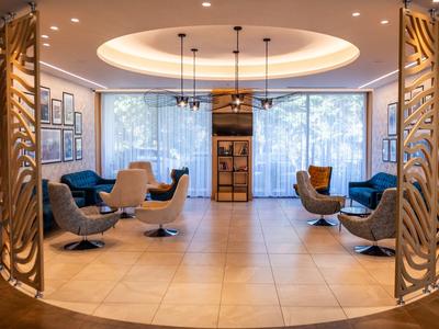 Elegantní hotelová lobby s moderními křesly a velkými okny za denního světla.