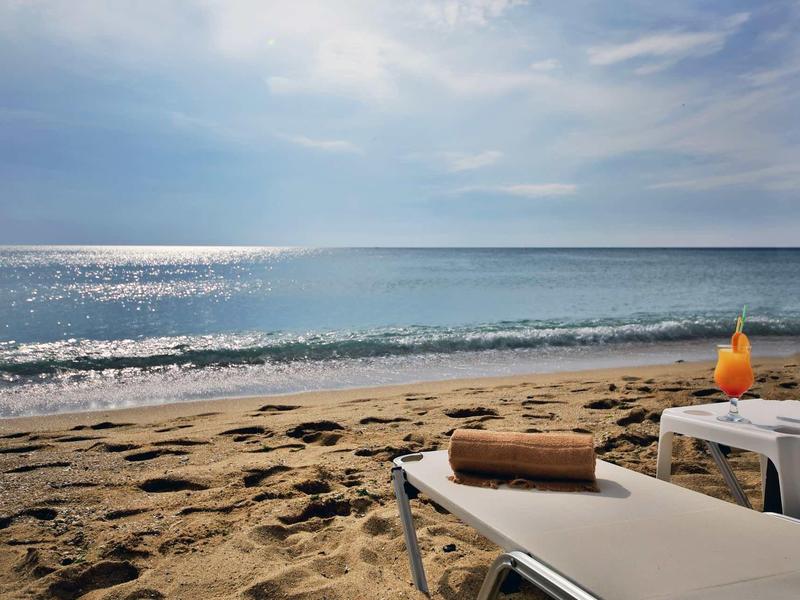 Strandzicht met ligstoelen, handdoeken en een drankje bij rustige zee en bewolkte lucht