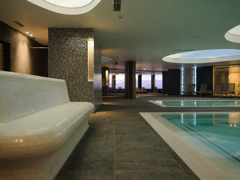 Modern binnenzwembad met verlichting en bank in een hotel