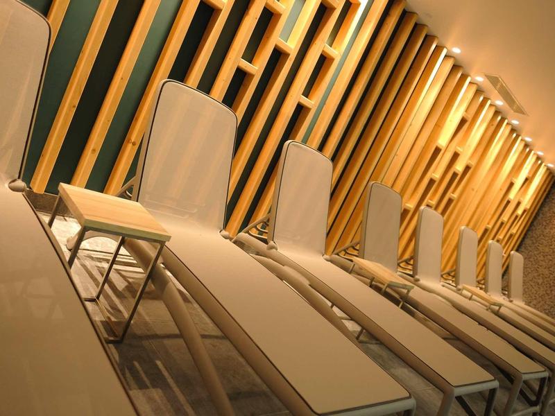 Vijf ligstoelen met kussens voor een muur met decoratieve houten latten in warm licht