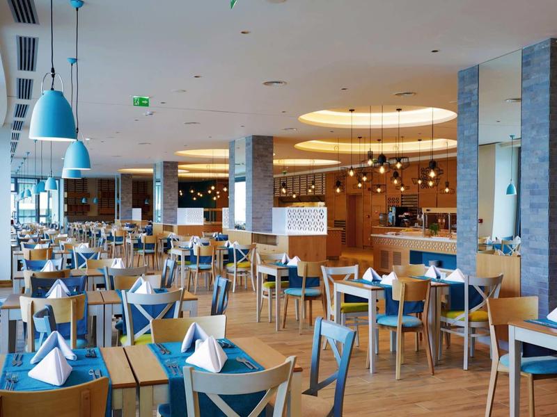 Licht restaurant met blauwe stoelen en elegant gedekte tafels.
