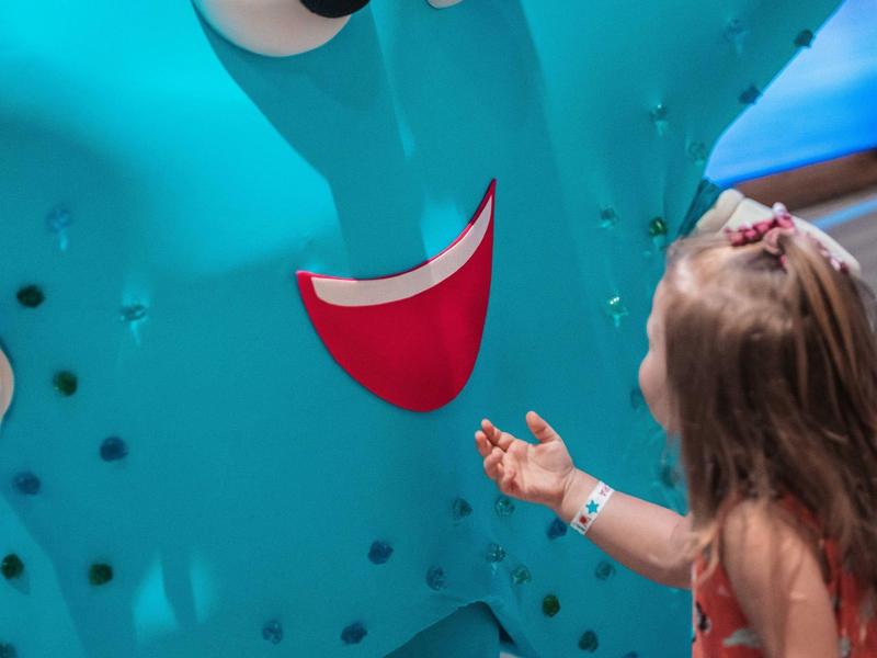 Malá dívka si hraje s velkou modrou usmívající se dekorativní hvězdicí.