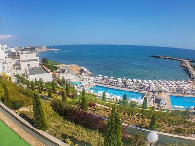 Vista di un hotel con piscine e area spiaggia sul mare sotto un cielo sereno.