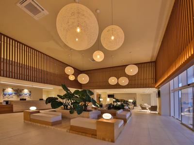 Elegante hall dell'hotel con illuminazione moderna, grande composizione di piante e finestre panoramiche