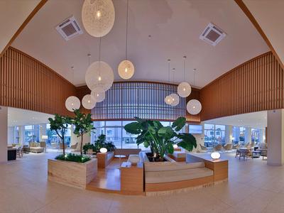 Moderne Hotellobby mit runden Hängelampen, Pflanzen und stilvollen Sitzbereichen in heller Umgebung.