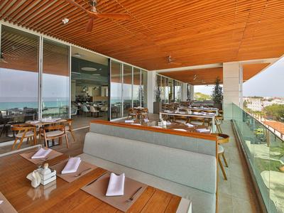 Moderne Hotelterrasse mit Sitzbänken, Tischen und Aussicht auf die Stadt und das Meer.