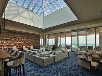 Lounge dell'hotel moderna con bar, divani e grande lucernario con vista sulla città.