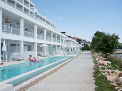 Moderner Hotelkomplex mit Zimmern, die Poolzugang bieten, neben einem Uferweg und Meer.