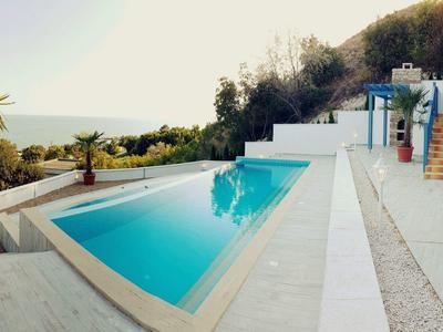 Area piscina moderna con vista tropicale e design bianco-blu