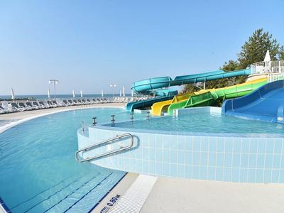 Piscina all'aperto vuota con scivoli d'acqua sotto un cielo limpido in un resort.