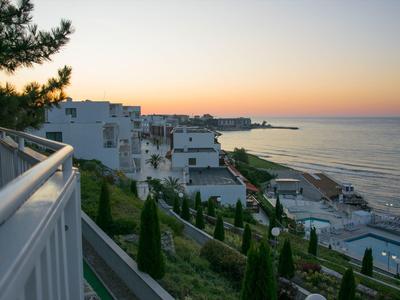 Camera d'albergo moderna e luminosa con letto, divano, TV e grande finestra con tende.