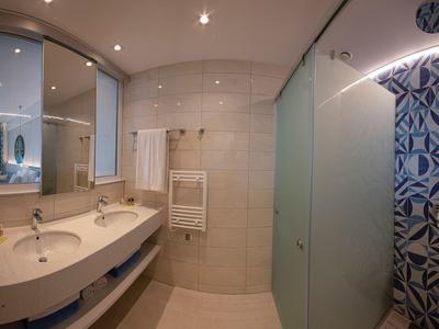 Bagno moderno con doppi lavandini, grandi specchi e porta in vetro per la doccia