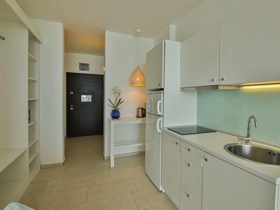 Angolo cottura compatto in una stanza d'hotel moderna e luminosa con porta nel corridoio.