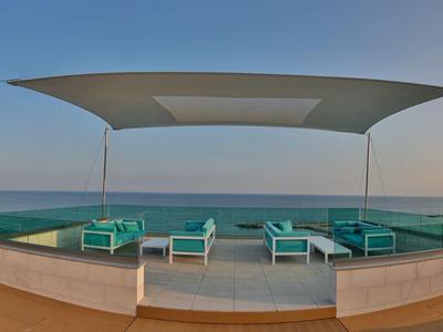 Moderner Infinity-Pool mit Liegestühlen und Aussicht auf das Meer bei Sonnenuntergang.
