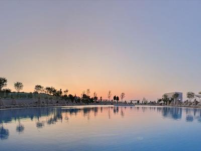Weitläufiger Pool bei Sonnenuntergang mit klarer Spiegelung und mediterraner Landschaft.