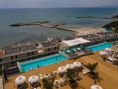 Vista di una piscina moderna dell'hotel con ombrelloni e lettini vicino al mare.