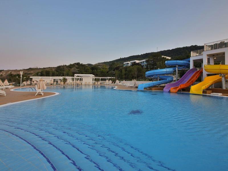 Grande piscina dell'hotel con scivoli d'acqua e lettini al crepuscolo.