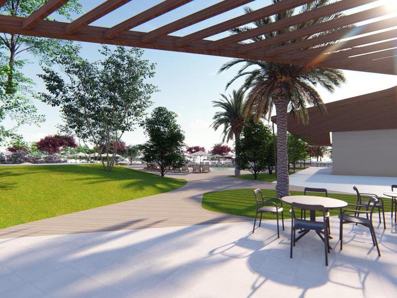 Vista di una terrazza soleggiata con tavoli e sedie accanto a un'area verde con alberi e palme.