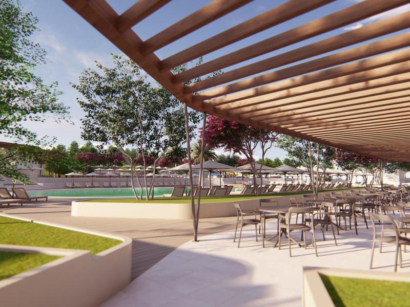 Terrazza soleggiata con tavoli e sedie accanto a prati verdi e piscine sotto un cielo azzurro.