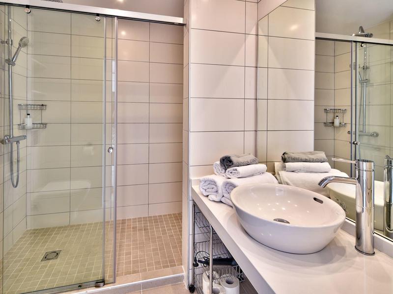 Bagno d'hotel moderno con grande specchio, doccia in vetro e lavandino elegante.