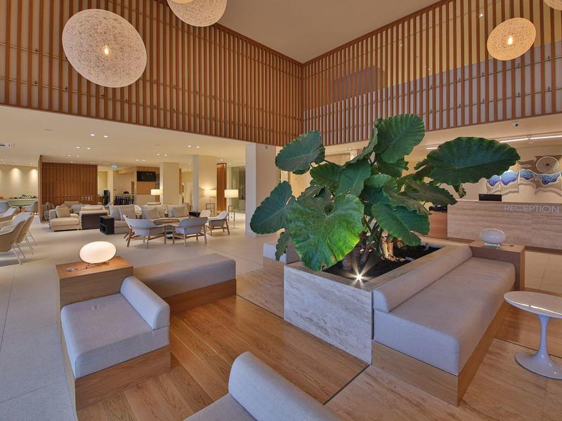 Lounge dell'hotel moderna con divani, piante e pavimento in legno caldo