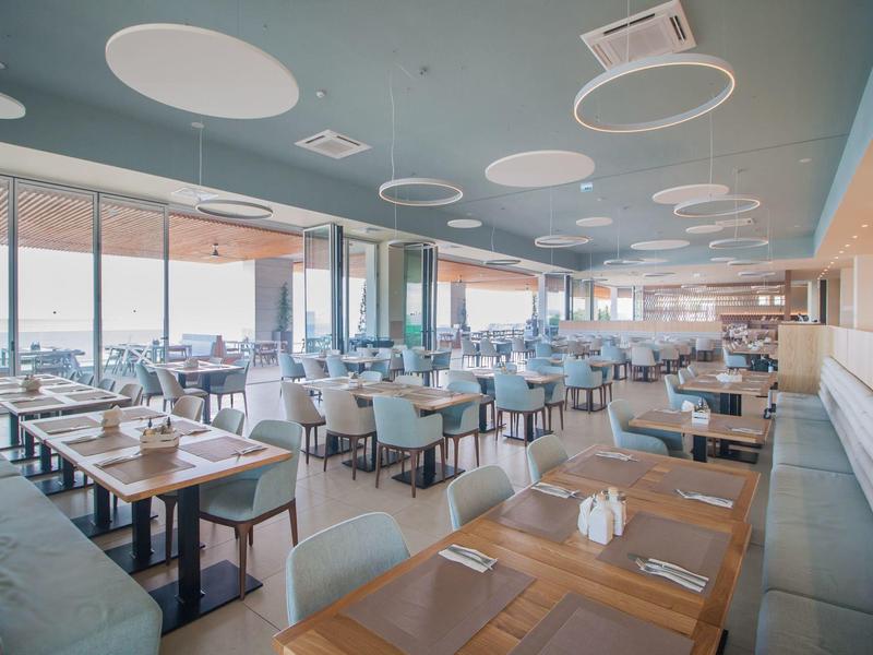 Ristorante luminoso e moderno con molti tavoli e grandi finestre con vista.