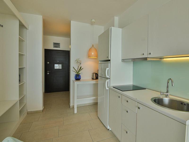 Angolo cottura compatto in una stanza d'hotel moderna e luminosa con porta nel corridoio.