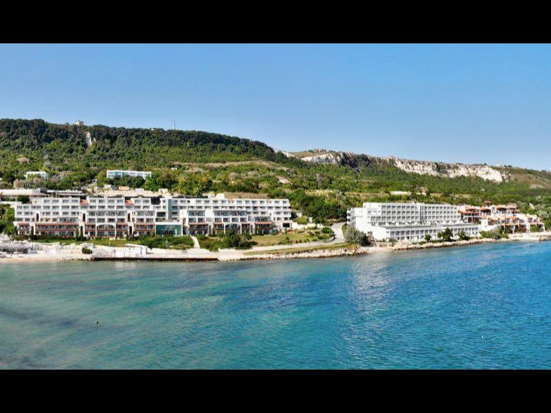 Costa con acqua limpida, spiaggia sabbiosa e hotel sotto un cielo azzurro.