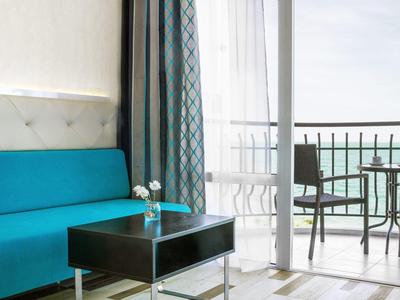 Chambre d'hôtel moderne avec canapé bleu et balcon avec table et deux chaises.