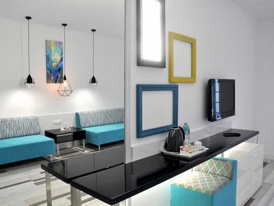 Salon d'hôtel moderne avec bancs bleus, décoration murale et télévision à écran plat.