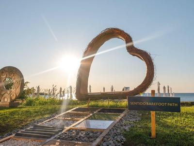 Sculpture en forme de cœur en bois et métal sur une pelouse sous un ciel clair