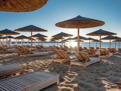 Plage avec parasols et chaises longues au coucher du soleil au bord de la mer.