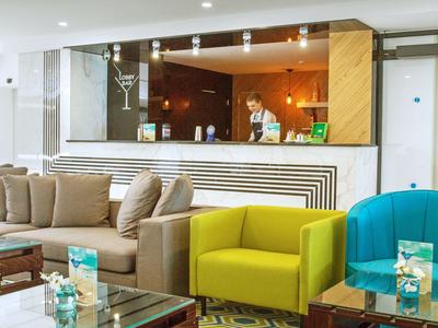 Hall d'hôtel moderne avec des fauteuils colorés confortables et un comptoir de réception en arrière-plan.