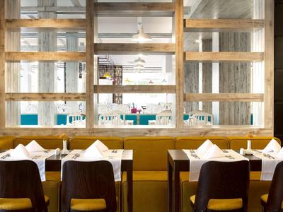 Vue d'une table dressée dans un restaurant moderne avec des chaises et un séparateur de pièce transparent.