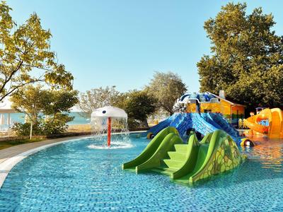 Piscine pour enfants avec toboggans aquatiques et jeu d'eau en extérieur d'un hôtel par temps ensoleillé.